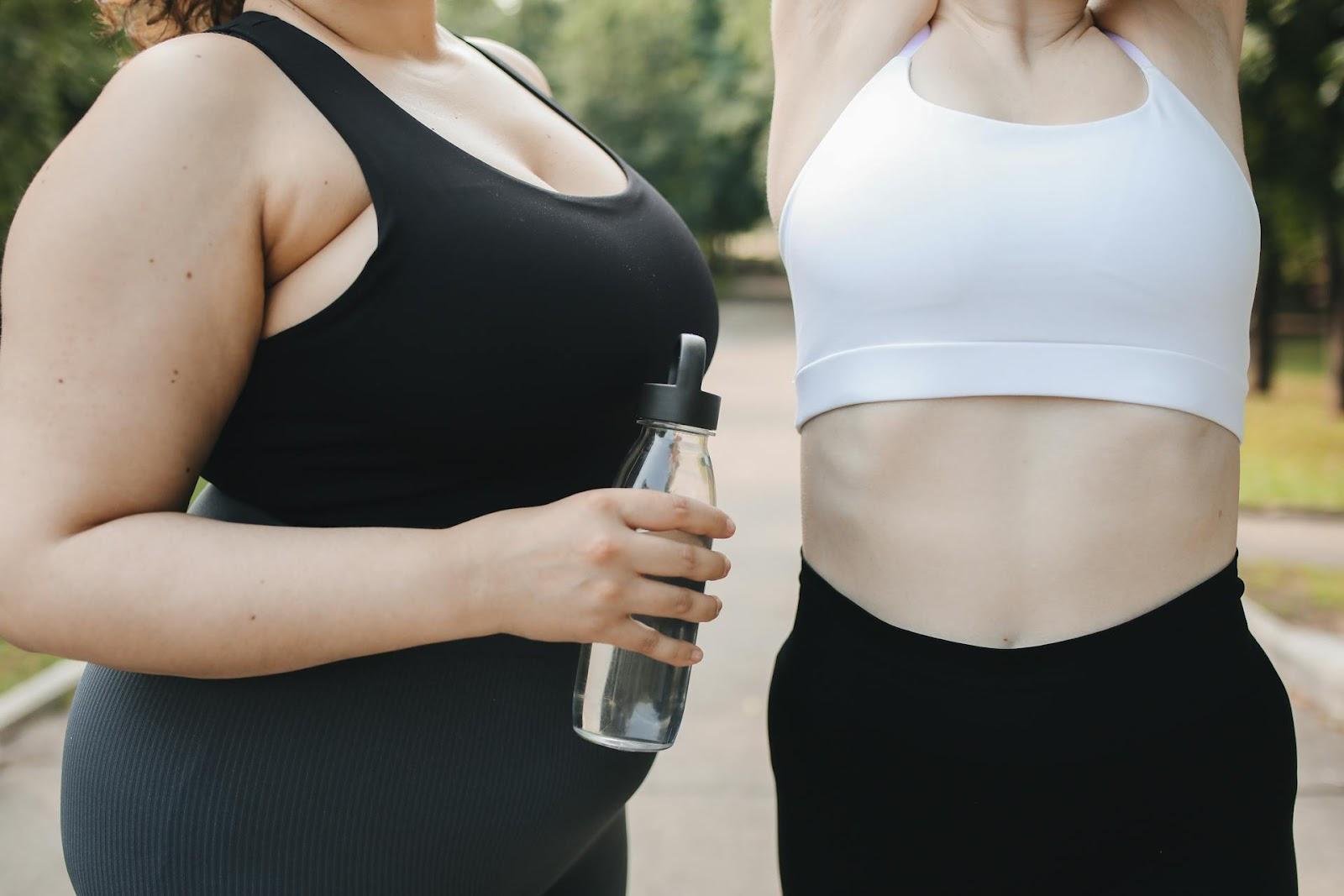 Two women exercising, one holding a water bottle, staying active and healthy with guidance from Lockport Urgent Care.
